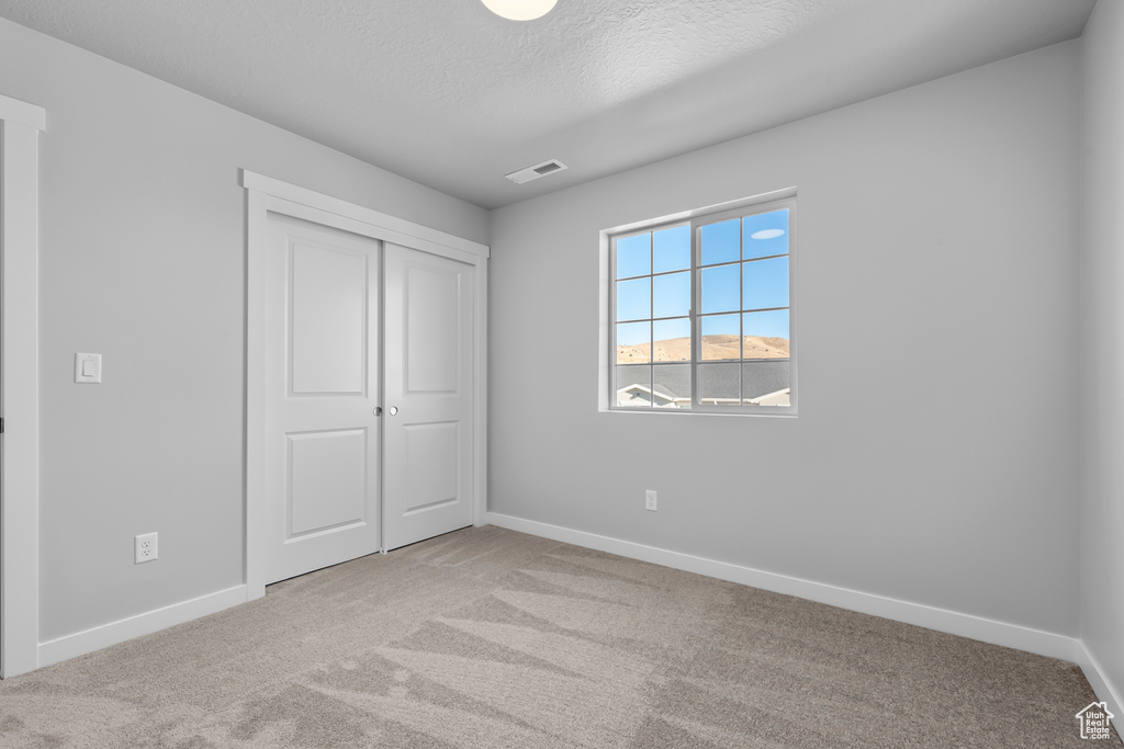 Unfurnished bedroom featuring baseboards, carpet, and visible vents