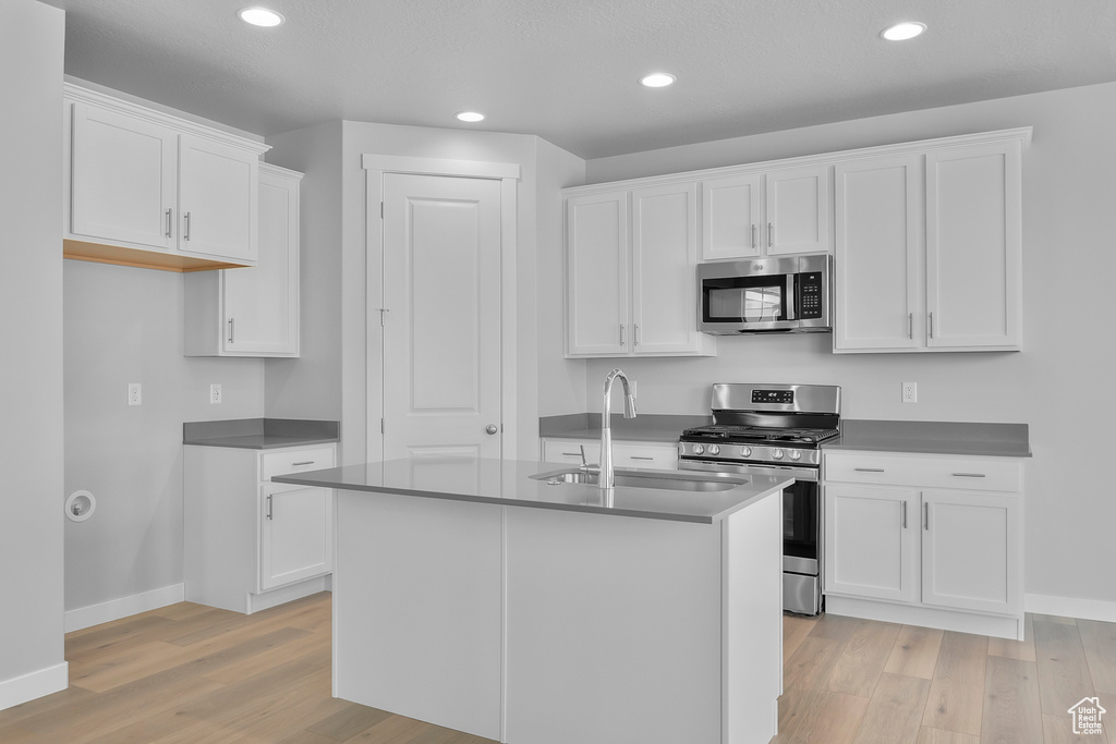 Kitchen featuring baseboards, a sink, light wood-style flooring, and appliances with stainless steel finishes