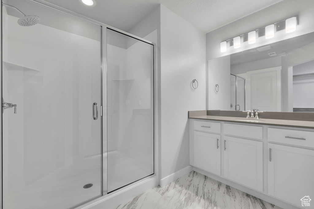 Full bathroom featuring vanity, baseboards, a shower stall, and marble finish floor