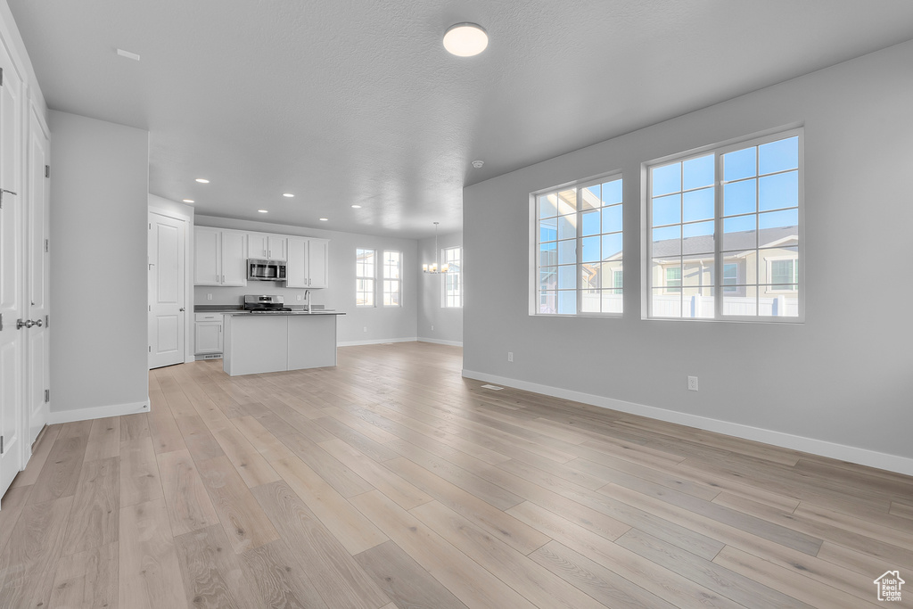 Unfurnished living room with recessed lighting, baseboards, and light wood-style flooring