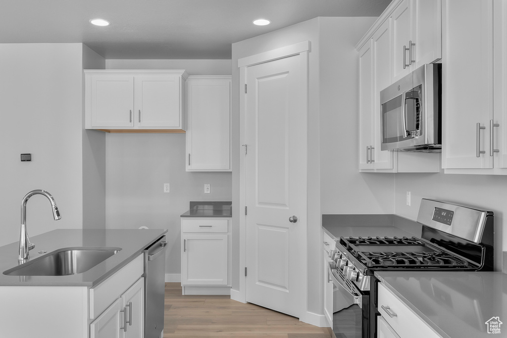 Kitchen with a sink, white cabinets, stainless steel appliances, and recessed lighting