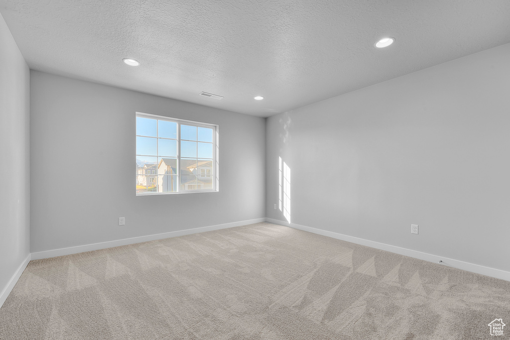 Carpeted empty room with recessed lighting, a textured ceiling, and visible vents