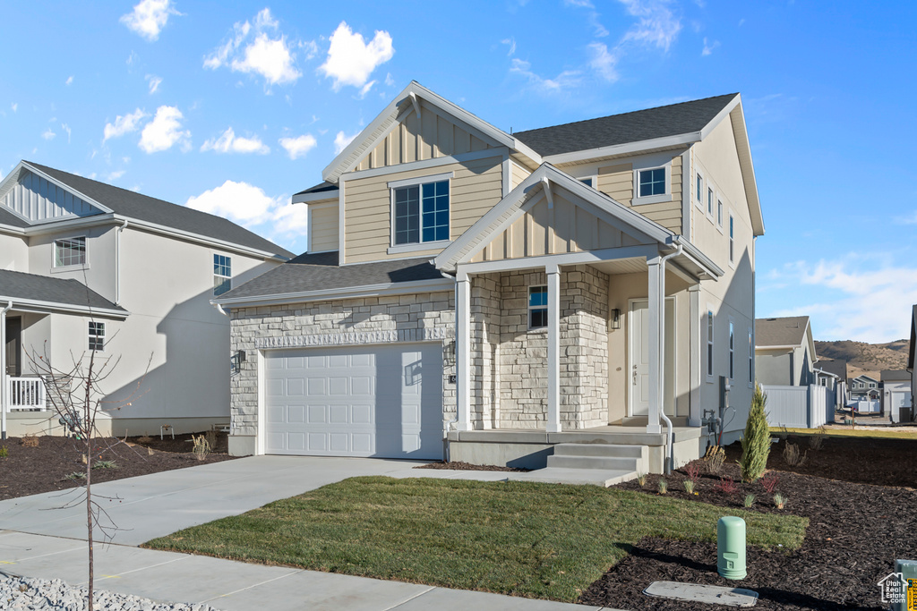 Traditional home with board and batten siding, concrete driveway, stone siding, and a garage
