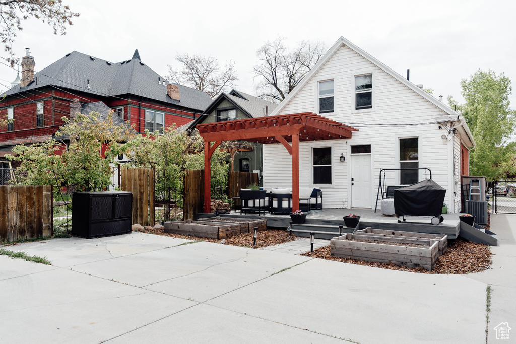 Rear view of property featuring a patio, a garden, fence, and a pergola