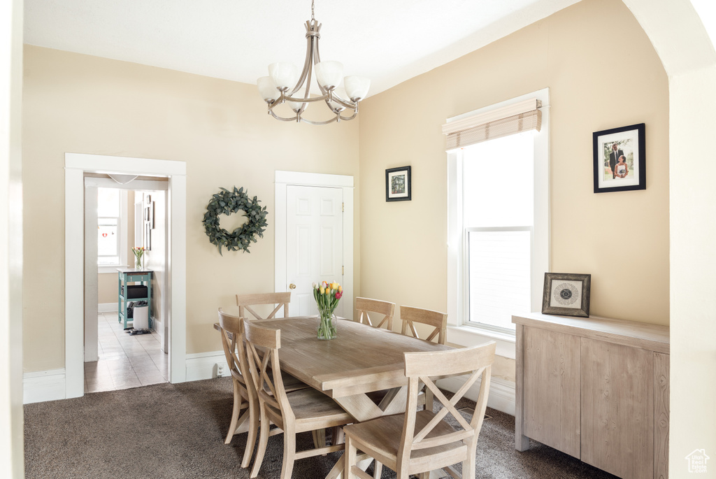 Dining room with a notable chandelier and light colored carpet