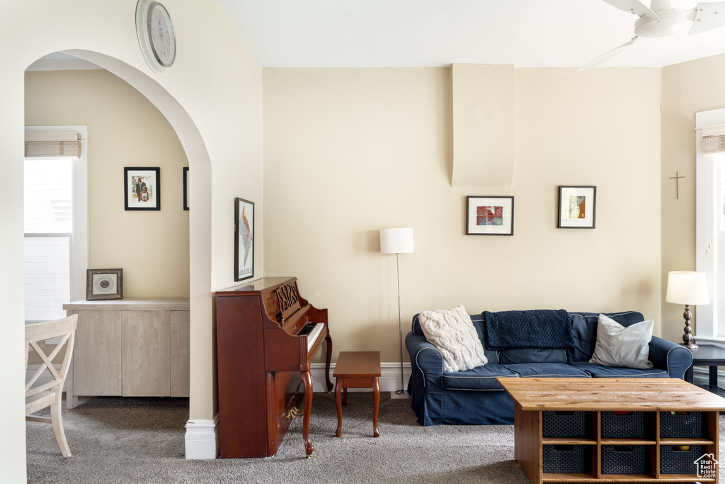 Carpeted living room with arched walkways and ceiling fan