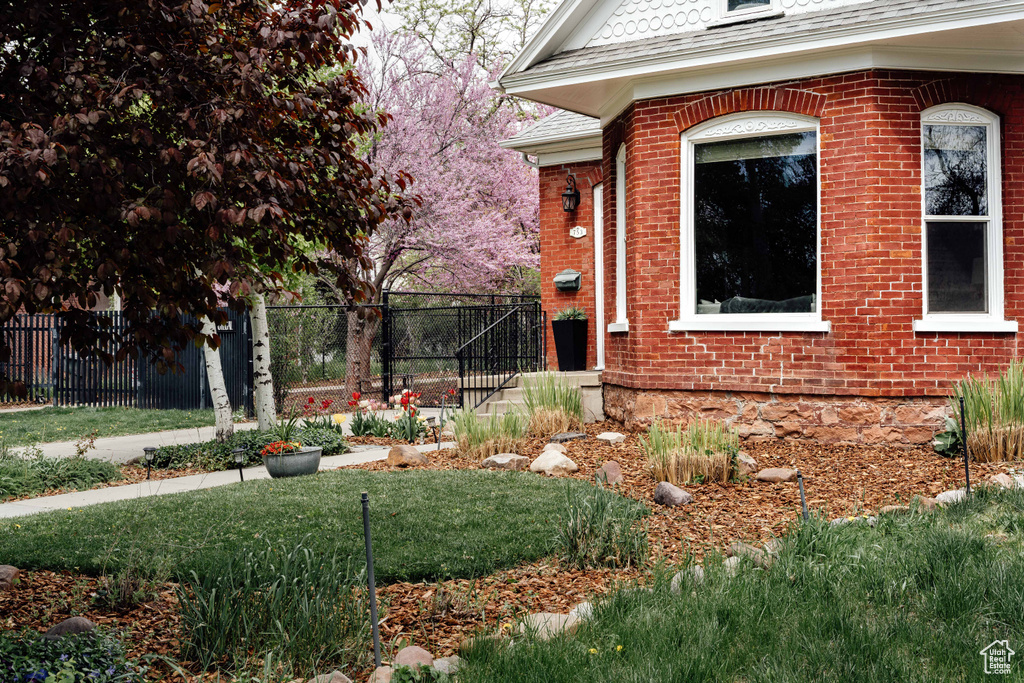 Exterior space with brick siding, fence, and a yard