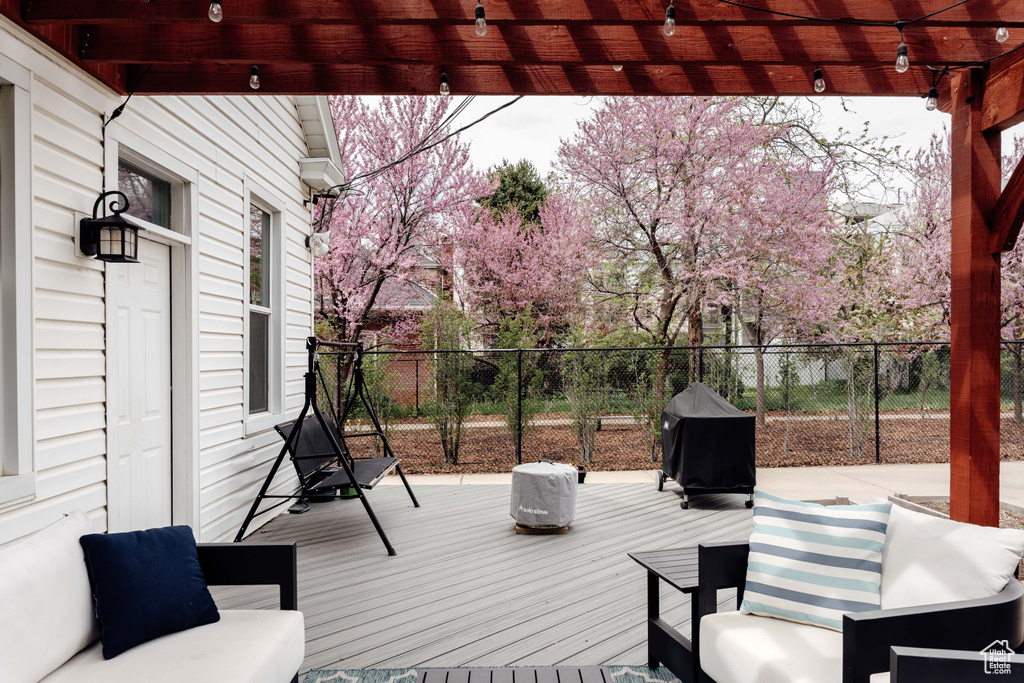 Wooden deck featuring grilling area, a pergola, and fence