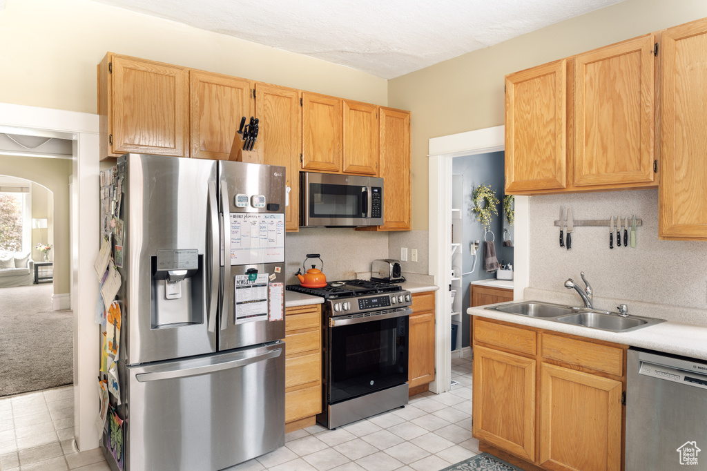 Kitchen with a sink, appliances with stainless steel finishes, light brown cabinets, and light countertops