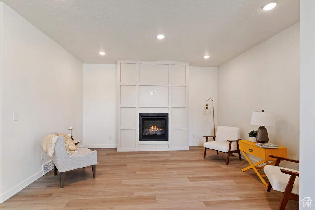 Sitting room with light wood-style flooring, recessed lighting, and a large fireplace