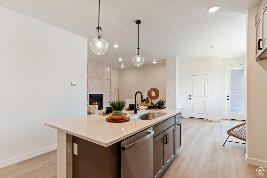 Kitchen featuring stainless steel dishwasher, light wood finished floors, light countertops, hanging light fixtures, and recessed lighting