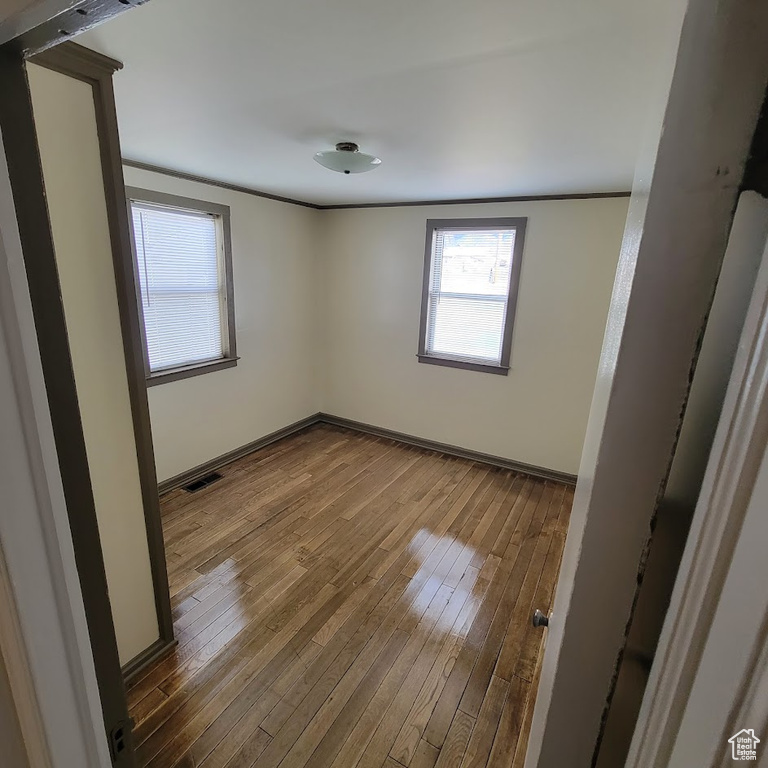 Spare room featuring baseboards, dark wood-style floors, and visible vents