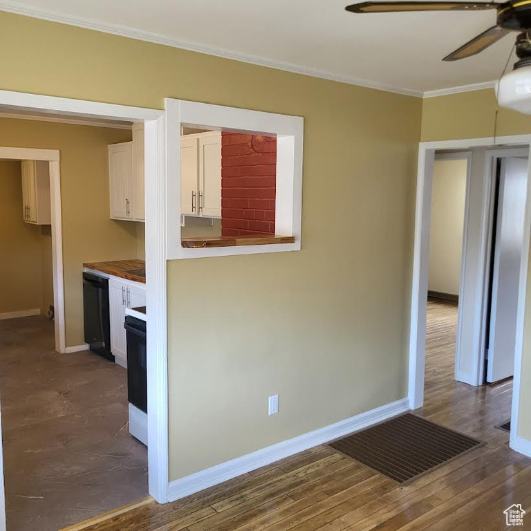 Kitchen featuring ornamental molding, baseboards, black dishwasher, white cabinets, and a ceiling fan