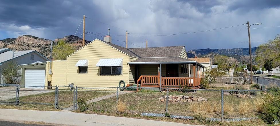 Bungalow featuring a garage, a mountain view, a fenced front yard, and a porch