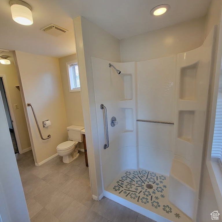 Bathroom featuring baseboards, walk in shower, toilet, and visible vents