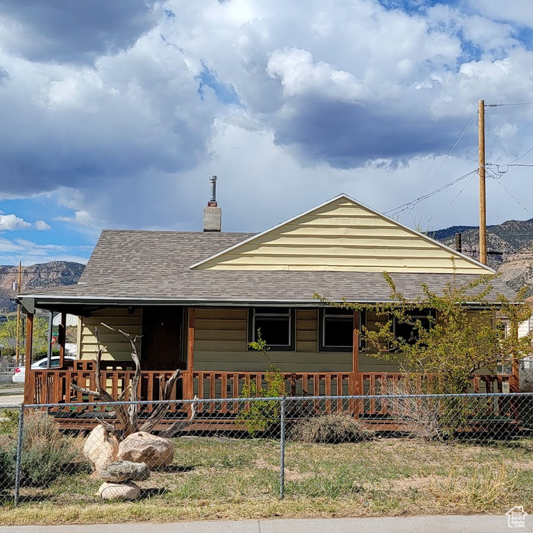 Farmhouse-style home with covered porch, fence, and a chimney