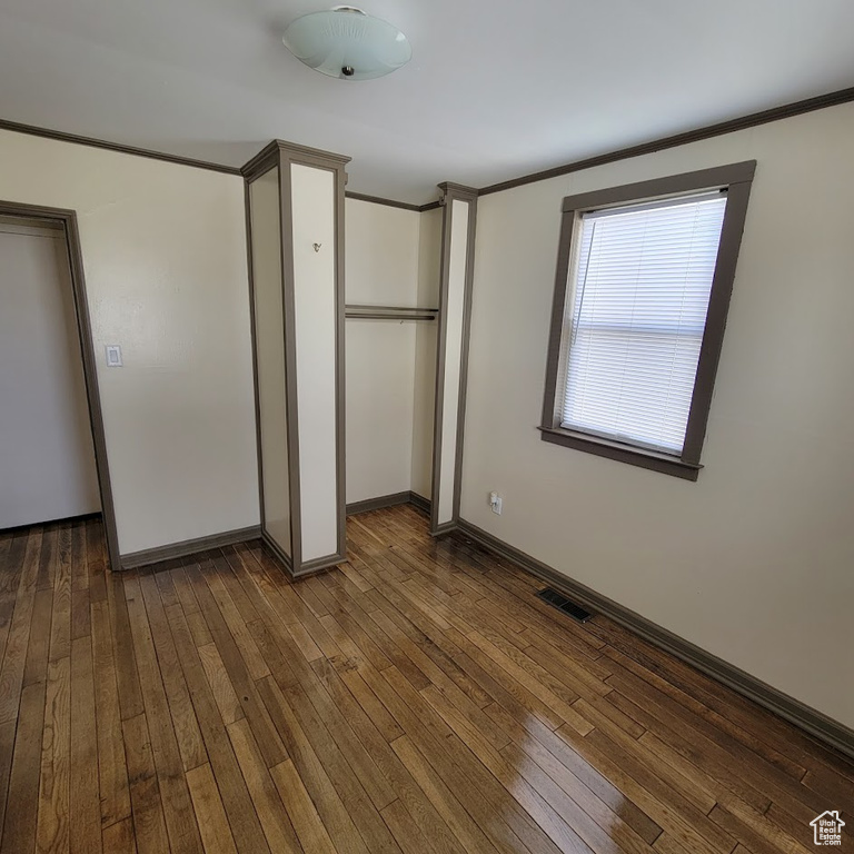 Unfurnished bedroom with baseboards, ornamental molding, hardwood / wood-style flooring, and visible vents