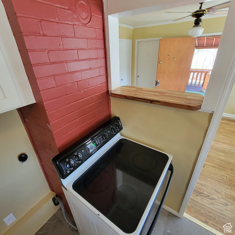 Laundry area with ceiling fan, laundry area, wood finished floors, baseboards, and ornamental molding