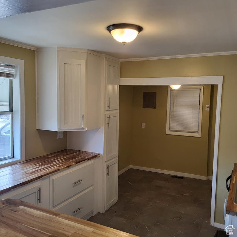 Kitchen with visible vents, ornamental molding, baseboards, white cabinets, and wood counters
