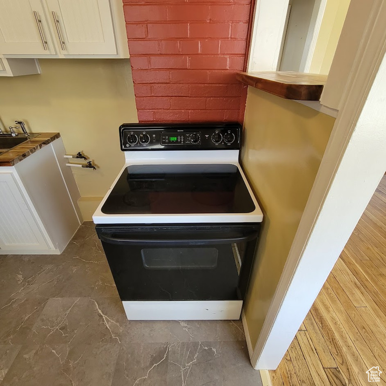 Room details with range with electric stovetop and white cabinetry