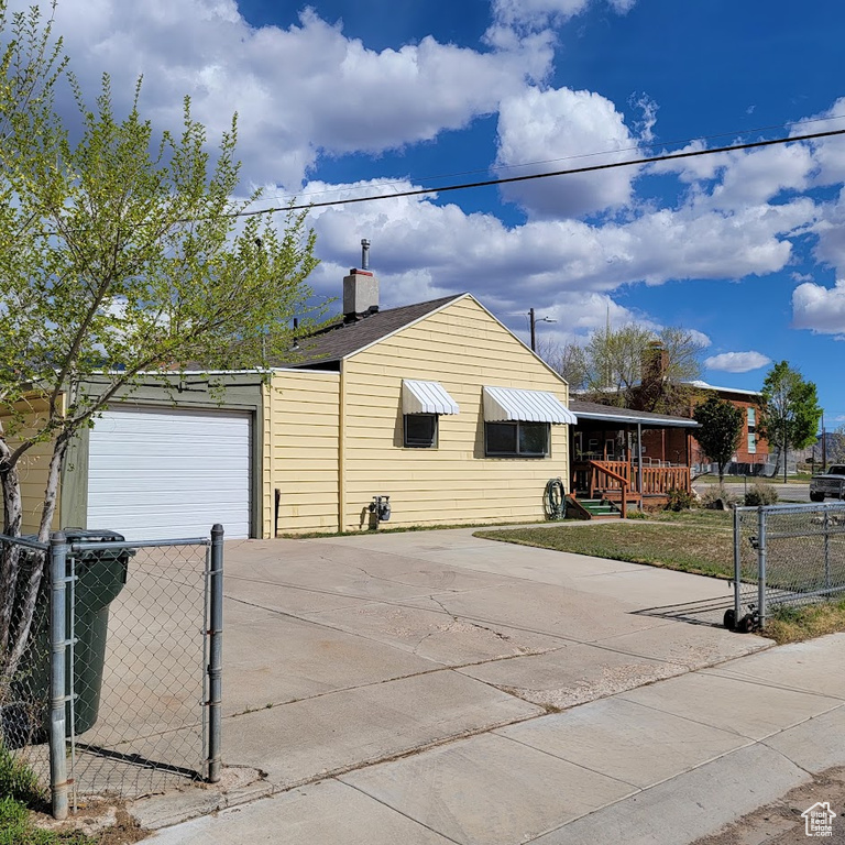 View of side of home featuring a garage, fence, driveway, and a chimney