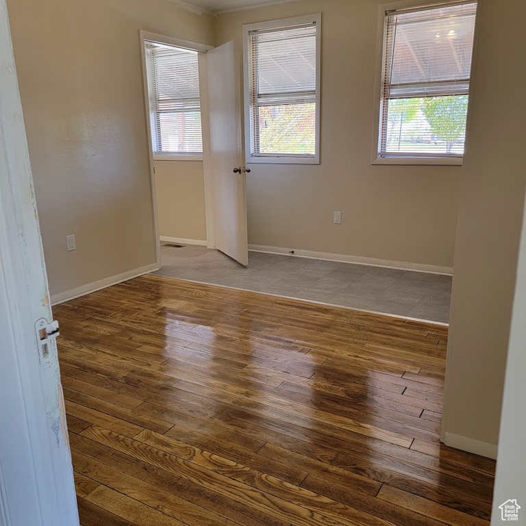Unfurnished room featuring baseboards, plenty of natural light, wood-type flooring, and ornamental molding