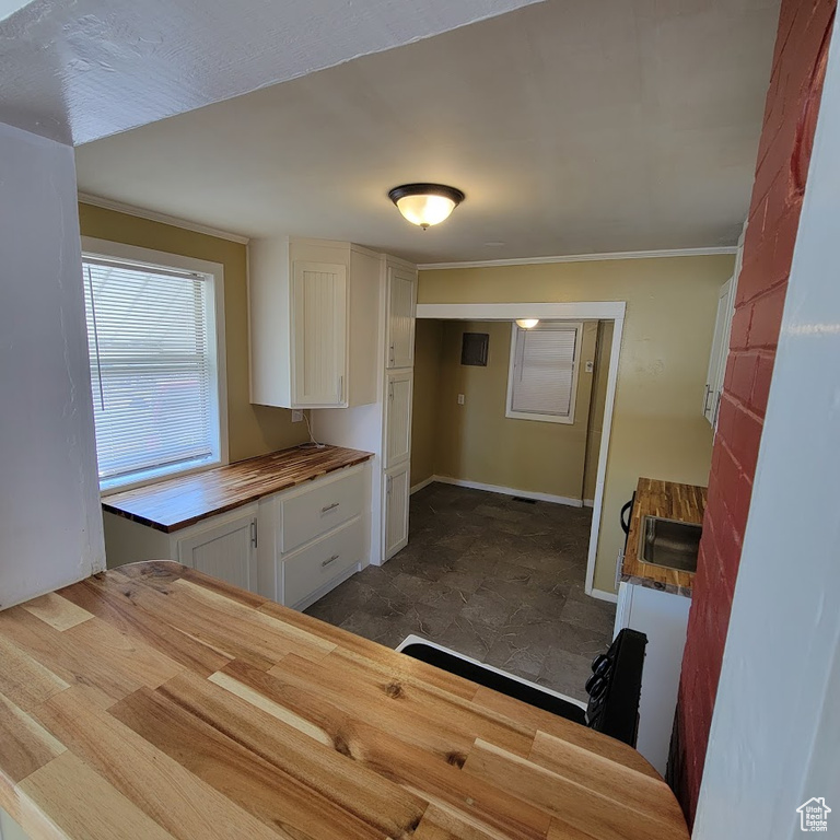 Kitchen featuring crown molding, a sink, white cabinetry, and wooden counters