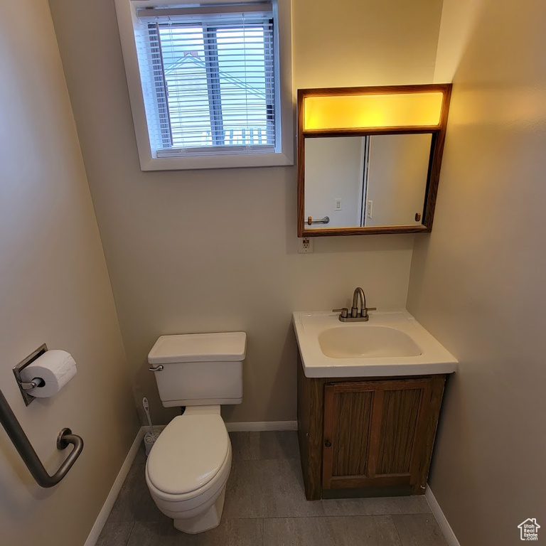 Bathroom with vanity, baseboards, tile patterned floors, and toilet
