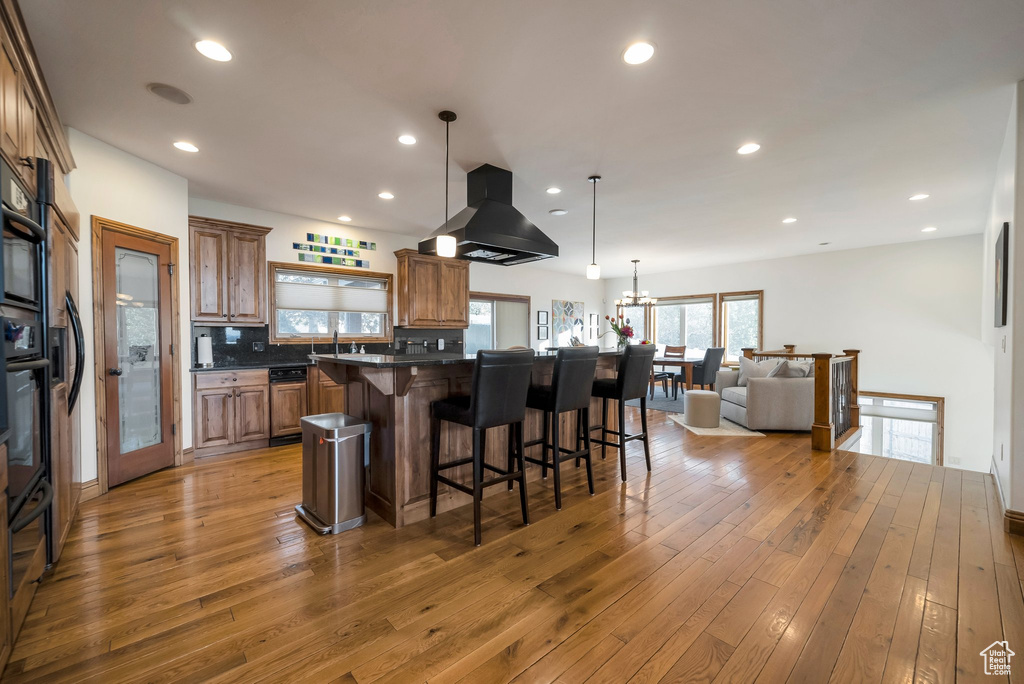 Kitchen with brown cabinets, dark countertops, a breakfast bar area, light wood-style flooring, and open floor plan