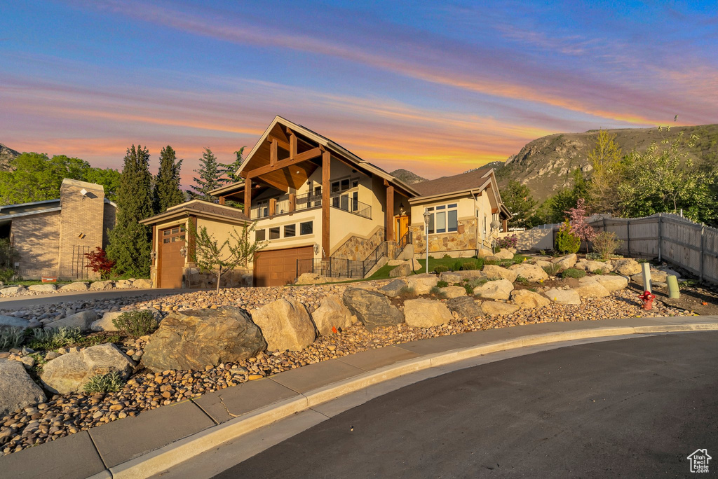 View of front of property featuring fence, a mountain view, stairs, stone siding, and stucco siding