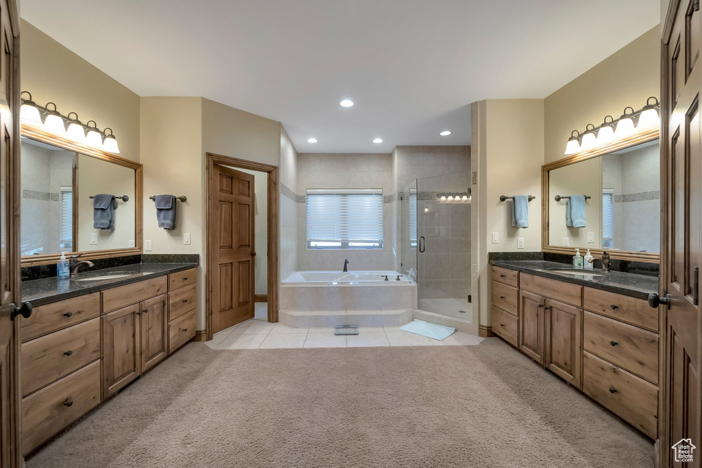 Full bathroom featuring two vanities, tile patterned floors, a shower stall, and a sink