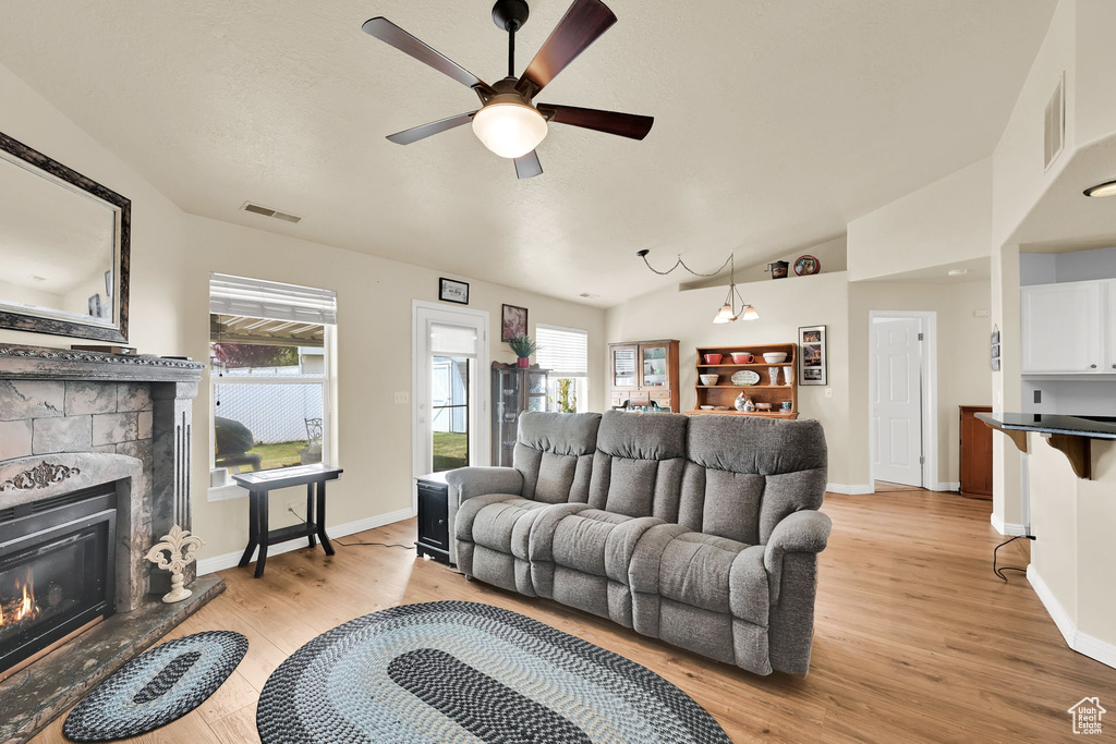 Living room with light wood-style floors, a wealth of natural light, a fireplace, and visible vents