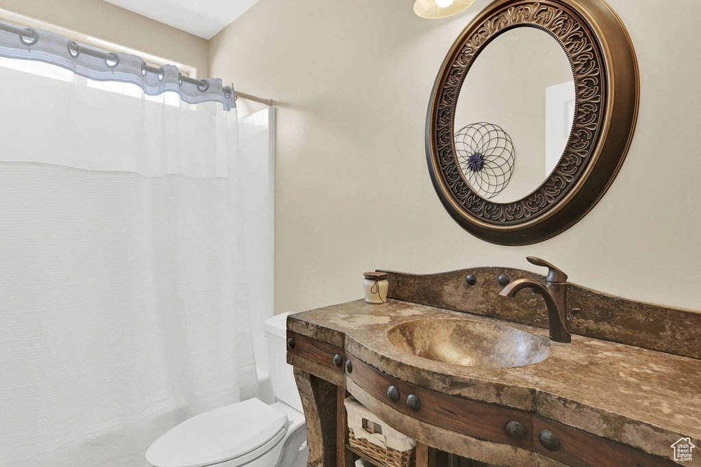 Full bath featuring toilet, a shower with curtain, and vanity
