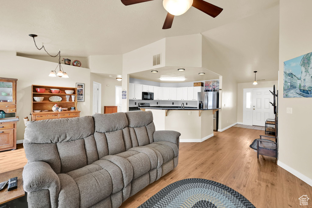 Living room featuring ceiling fan, visible vents, baseboards, and light wood finished floors