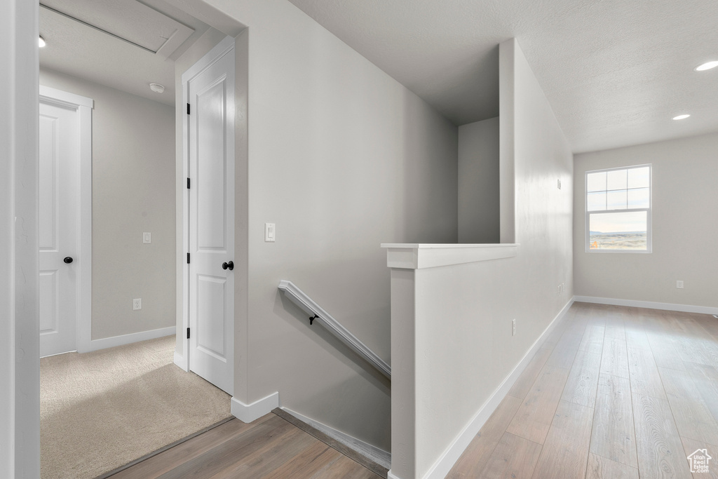 Corridor with baseboards, recessed lighting, wood finished floors, and an upstairs landing