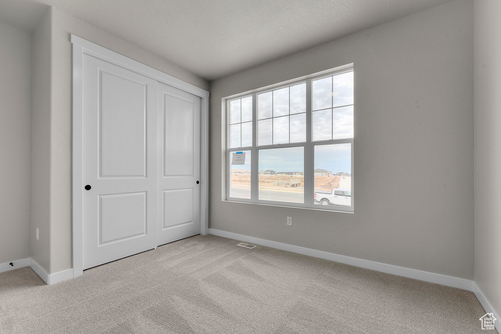 Unfurnished bedroom with baseboards and light colored carpet