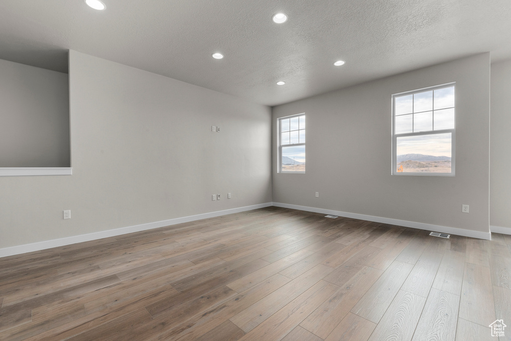 Unfurnished room featuring recessed lighting, baseboards, wood finished floors, and visible vents