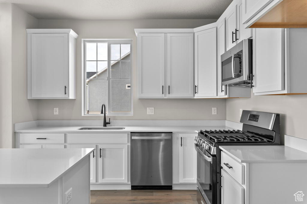 Kitchen with light countertops, white cabinetry, appliances with stainless steel finishes, and a sink