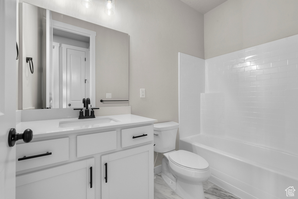 Bathroom with vanity, baseboards, toilet, marble finish floor, and shower / bathtub combination