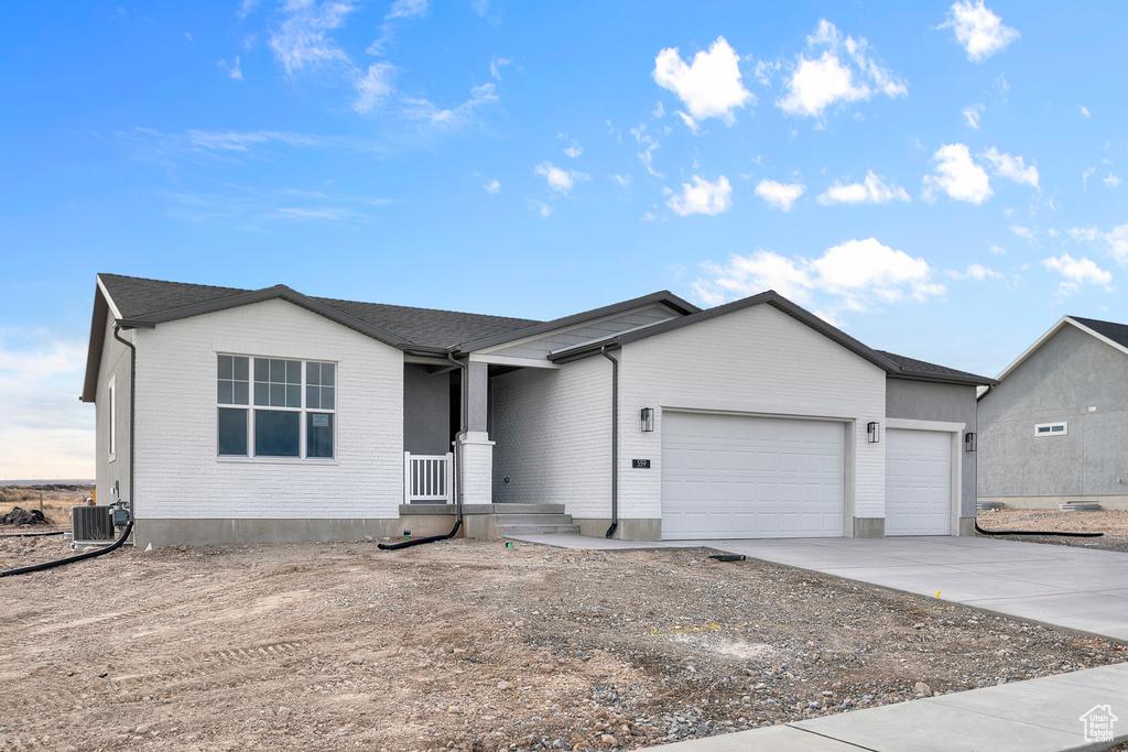 Single story home with a garage, central air condition unit, concrete driveway, and brick siding