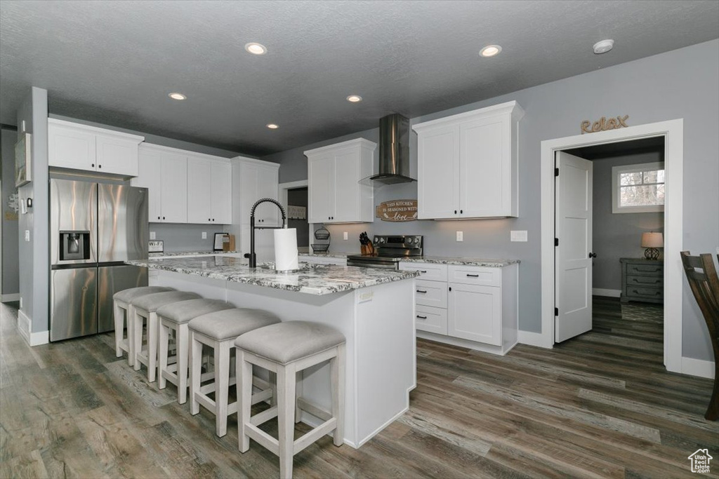 Kitchen with baseboards, a sink, wall chimney range hood, appliances with stainless steel finishes, and dark wood finished floors