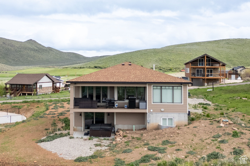 Rear view of house with a hot tub and a mountain view