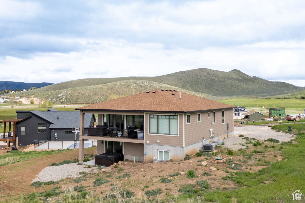 Back of property with a patio area, roof with shingles, and a deck with mountain view