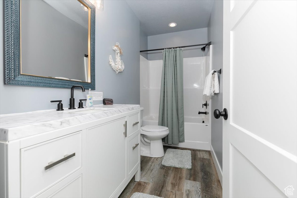 Full bath featuring vanity, recessed lighting, toilet, wood finished floors, and shower / tub combo with curtain
