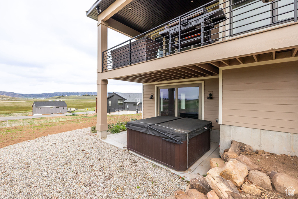 View of patio / terrace with a hot tub, a balcony, and a mountain view