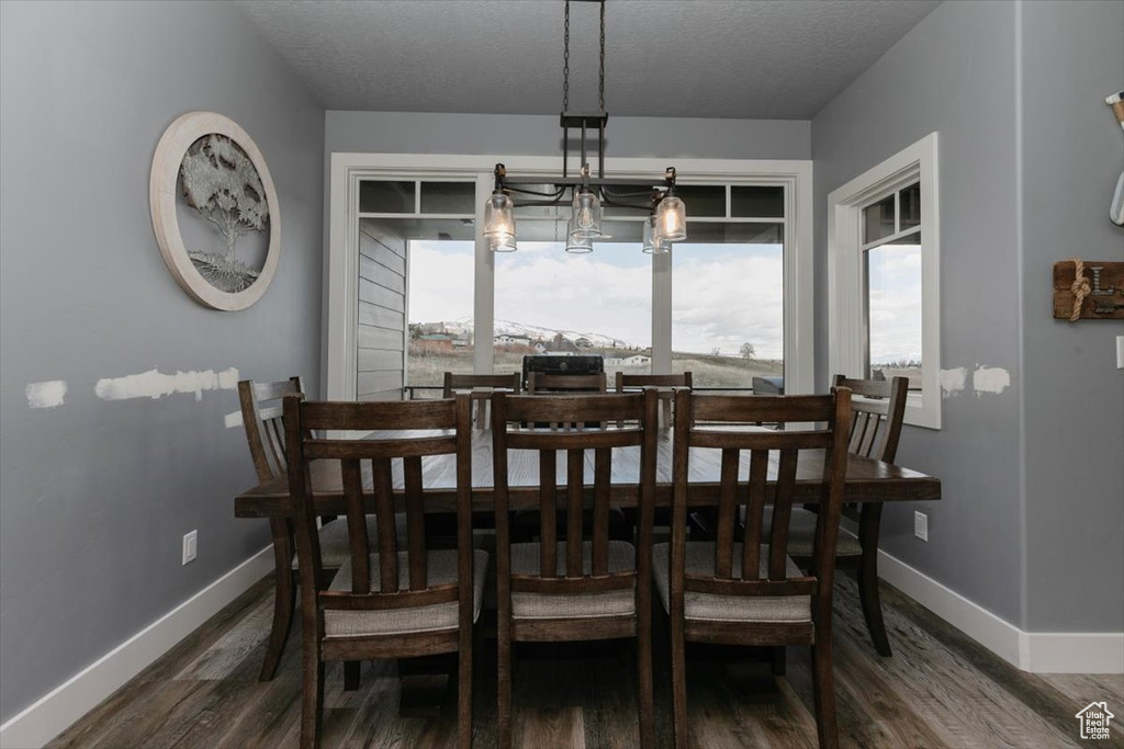 Dining area with a textured ceiling, wood finished floors, and baseboards