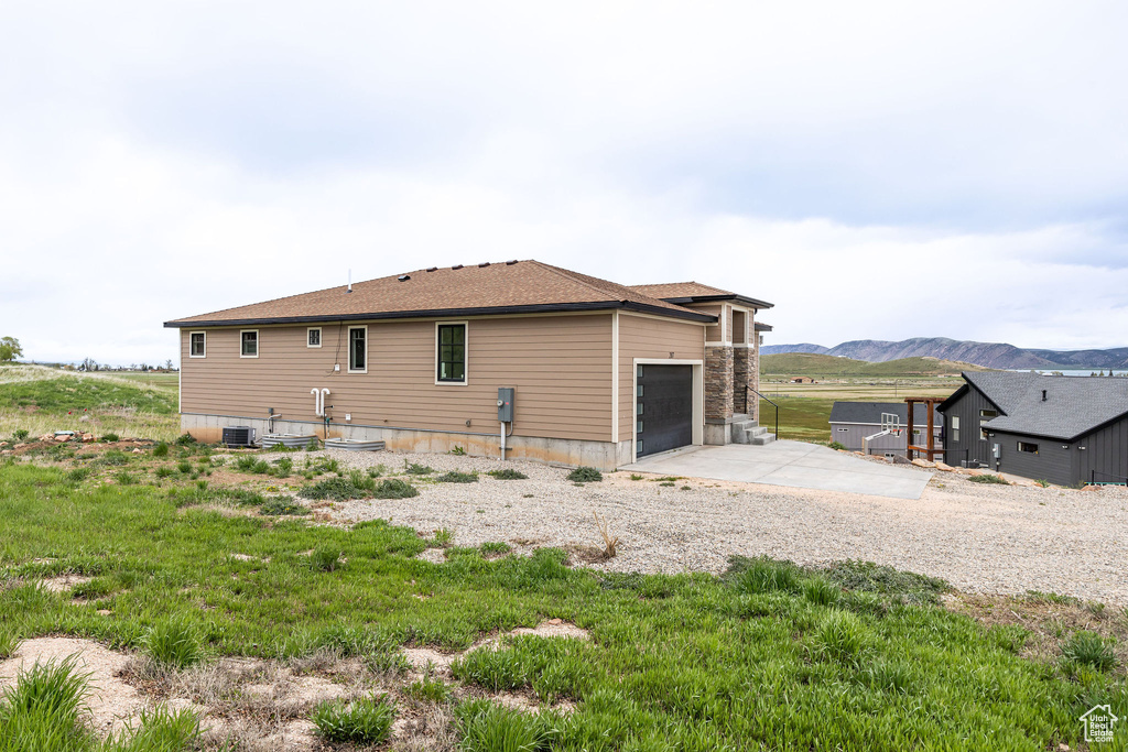 View of property exterior featuring an attached garage, a mountain view, concrete driveway, and central AC unit