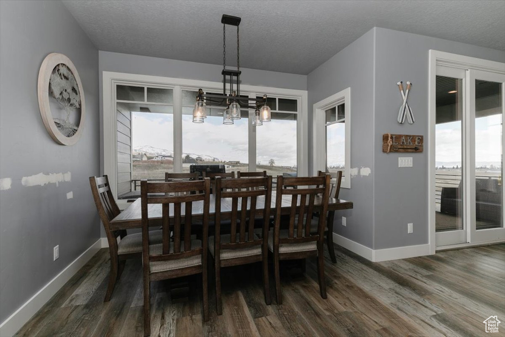 Dining space featuring a chandelier, a textured ceiling, baseboards, and dark wood-style floors