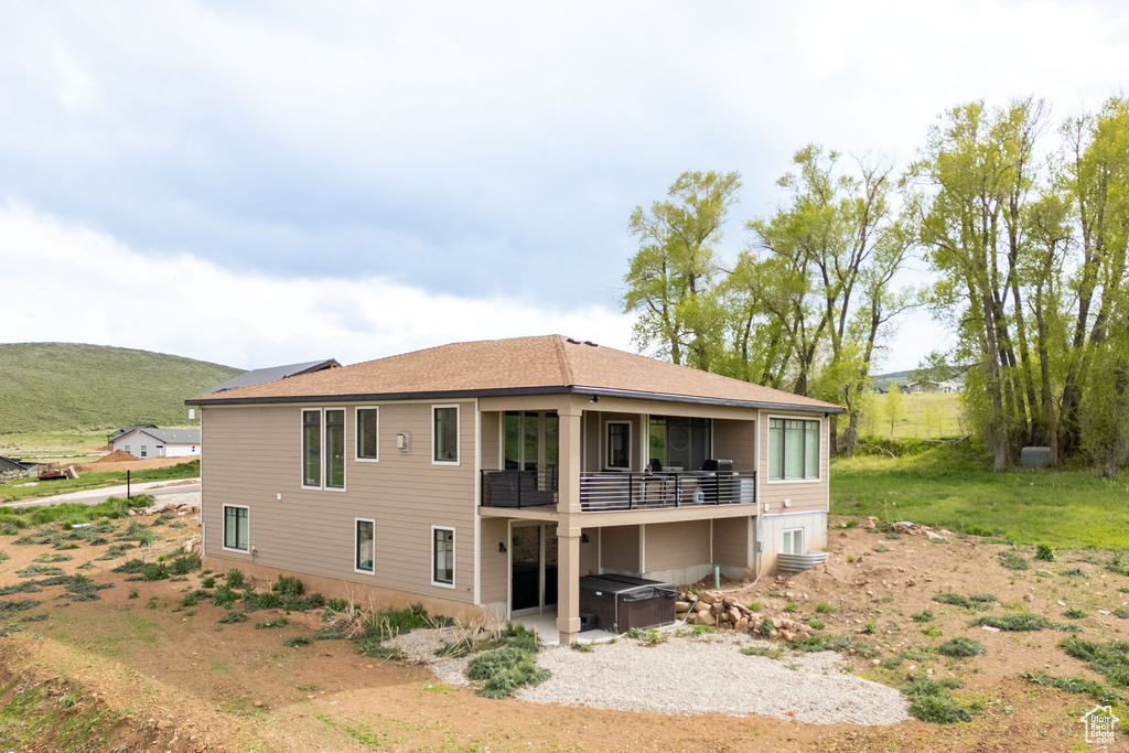 Rear view of house featuring a hot tub and a balcony