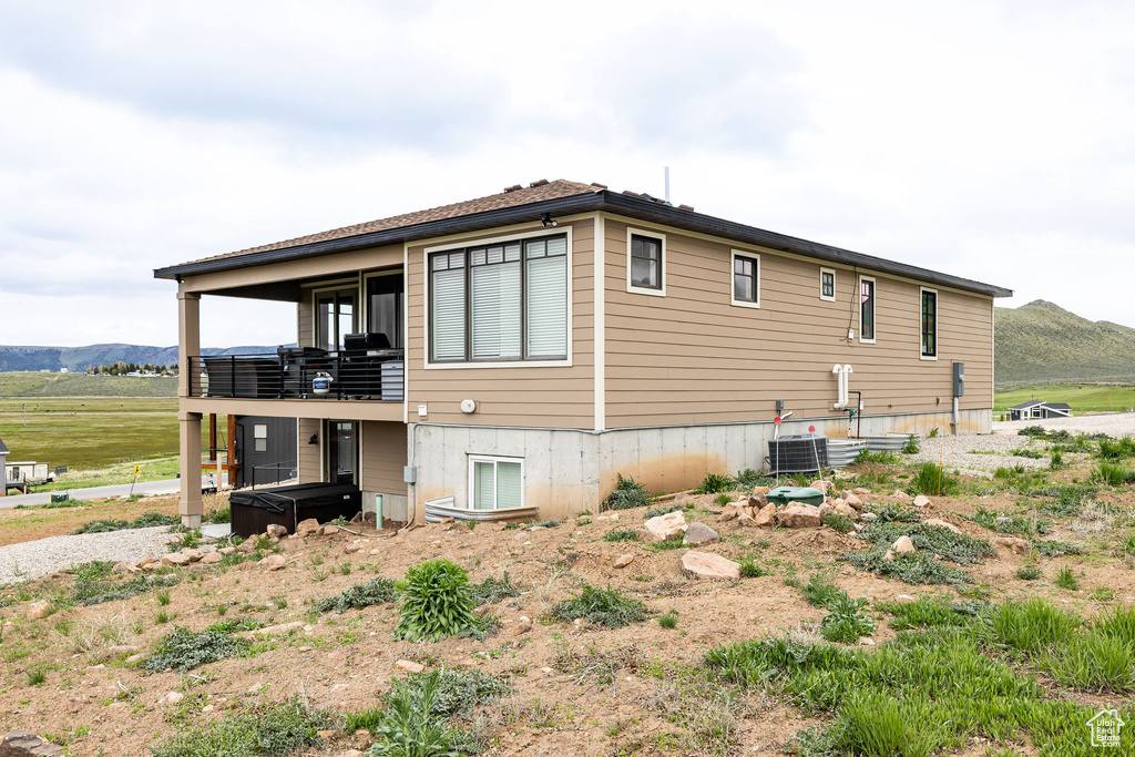View of side of property featuring a hot tub, a mountain view, and central air condition unit